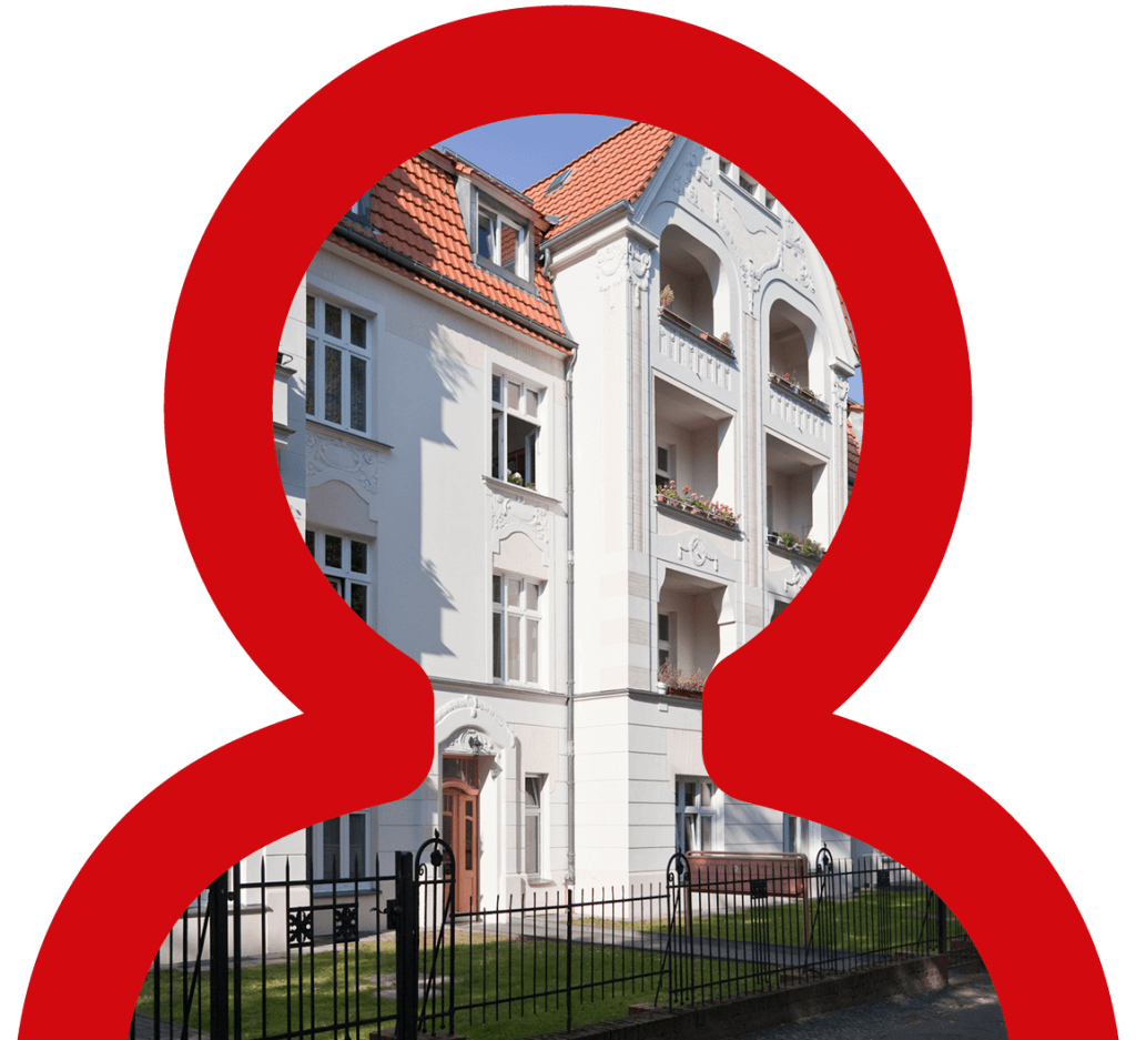 Mehrstöckiges Gründerzeithaus mit weißer Fassade, Ziegeldach und verziertem Vorgartenzaun